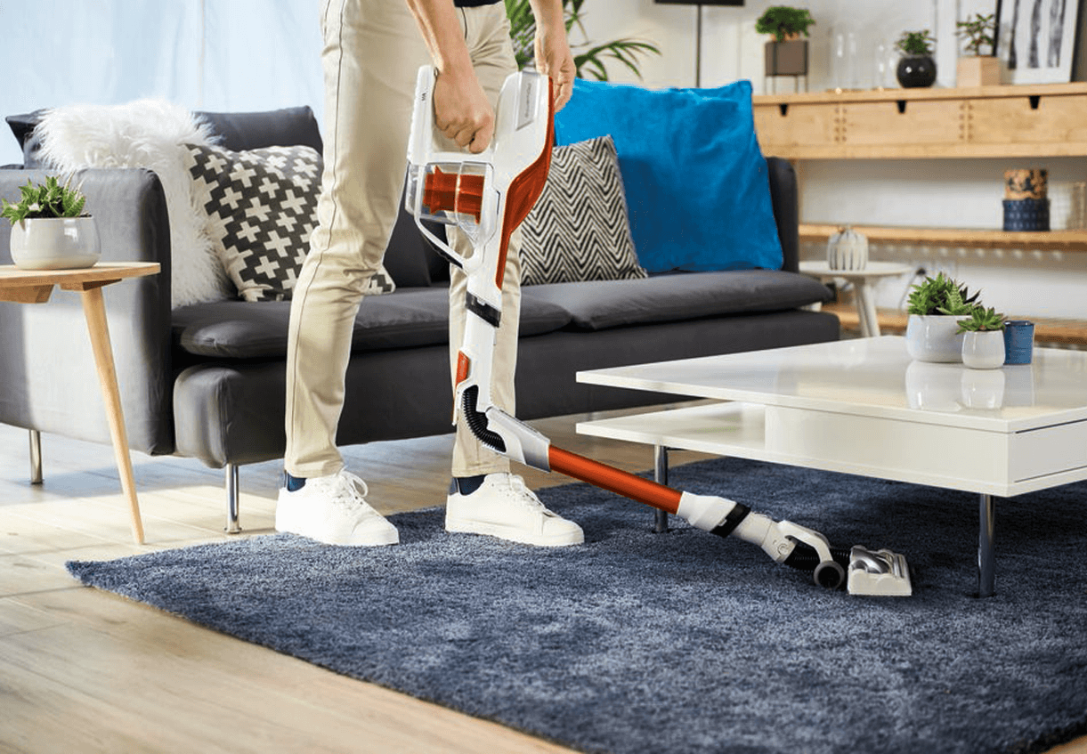 Man vacuuming under a white table